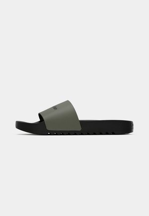 Ansicht von der Seite eines schwarzen Rutschsandals mit einem olivgrünen breiten Riemen und einer strukturierten Sohle.