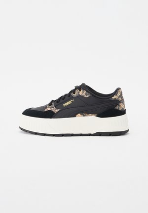 Czarno-beżowy sneaker Puma z wzorem skóry węża, grubą białą podeszwą, sznurowanym designem i złotym logo Puma z boku.