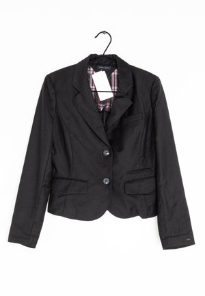 Black blazer with two front buttons, notched lapels, and two pockets. Lined with red and black plaid pattern. Hangs on a black hook.