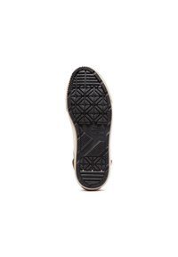 Semelle de chaussure en caoutchouc noir avec des motifs de grip texturés, présentant un accent latéral beige et le logo "Converse All Star" au fond.