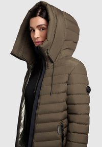 Chaqueta acolchada en verde oliva, con una gran capucha, cierre de cremallera, bolsillos laterales y textura de acolchado con un forro brillante.
