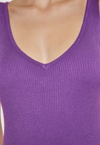 Top violet cu dungi, având un decolteu adânc în V și un material tricotat texturat, evidențiind o siluetă ajustată și o suprafață netedă.