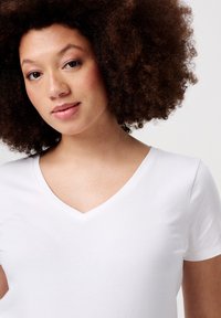 Witte v-hals t-shirt van zacht materiaal, met korte mouwen en een gladde textuur. Close-up van de halslijn en het bovenlichaam.