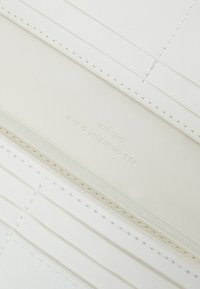 White leather wallet featuring stitched accents, a zip closure, and embossed branding reading "VALENTINO" and "MARIO VALENTINO SPA."