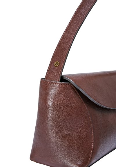 Sac à main en cuir marron avec un rabat courbé et une bandoulière simple, présentant un petit emblème doré sur la bandoulière près de la couture.