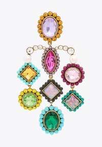 Boucles d'oreilles colorées audacieuses ornées de pierres de différentes formes dans des teintes de violet, vert, jaune et bleu ; montées sur un métal doré.