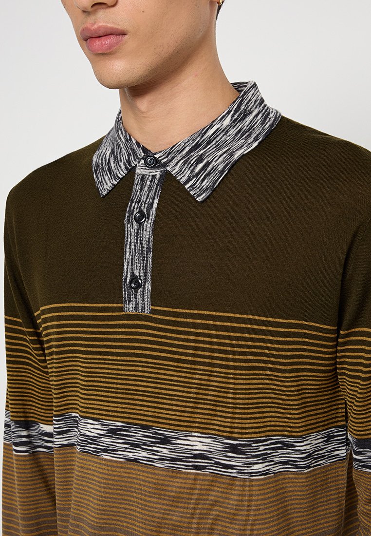 Langarmshirt in Olivgrün mit horizontalen Senfgelb Streifen. Mit einem gemusterten Schwarz-Weiß-Kragen und Knopfblende.