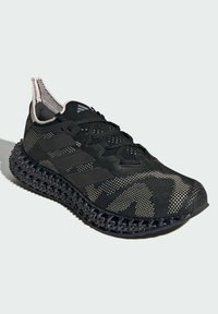 Black athletic sneaker featuring a textured mesh upper with a camouflage pattern, three stripe accents, and a patterned rubber sole.