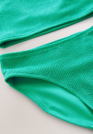 Top e slip bikini verdi con una texture a maglia unica. L'interno è liscio, con un bordo cucito pulito.