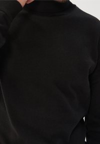 Czarny golf wykonany z prążkowanej dzianiny, z dopasowanym krojem i bezszwowym kołnierzem. Gładka faktura, minimalistyczny styl.