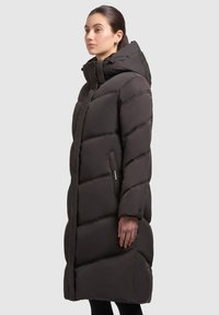 Long black puffer coat with a hood, featuring stitched sections, zippered side pockets, and a smooth, matte texture.