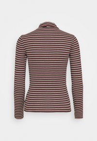 Långärmad,figurnära topp med hög krage. Har horisontella ränder i röd, vit och marinblå, tillverkad av ett mjukt stickat material.