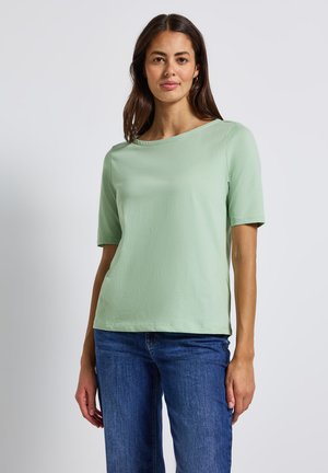 Kortærmet, lysegrøn top i et blødt stof med rund halsudskæring og afslappet pasform, parret med blå denim jeans. Simpelt og alsidigt design.