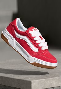 Adidași roșii cu un exterior din nubuc, accente albe �și șireturi. Dispun de o cutie de vârf perforată și o talpă din cauciuc gumos. Design rotunjit și bine amortizat.