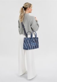 Blue canvas handbag with a tie-dye pattern, two handles and a detachable shoulder strap, featuring the logo "Coach New York" on the front.