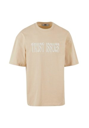 Beige katoenen t-shirt met korte mouwen, met de tekst "TRUST ISSUES" in het wit, met een ontspannen pasvorm.