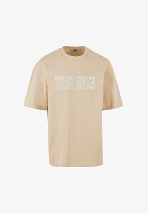 Beige katoenen t-shirt met korte mouwen, met de tekst "TRUST ISSUES" in het wit, met een ontspannen pasvorm.