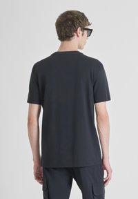 T-shirt noir à manches courtes en coton, avec un col rond et un ourlet droit. Le tissu a une texture lisse, offrant un look décontracté.