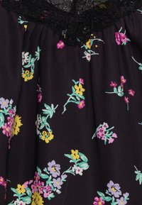 Czarna tkanka z kwiatowym wzorem, na którym znajdują się żółte, różowe i turkusowe kwiaty. Czarny koronkowy wykończenie przy dekolcie dodaje faktury i szczegółów.
