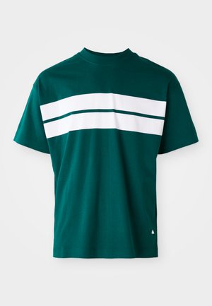 T-shirt en coton teal avec un col rond, des manches courtes et des rayures blanches horizontales sur la poitrine. Coupe légèrement décontractée.