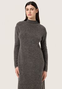 Abito lungo e aderente in tessuto knit grigio scuro con colletto a mordente e maniche lunghe. Tessuto liscio senza motivi o dettagli visibili.