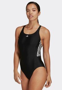 Maillot de bain noir au design épuré, avec des rayures blanches Adidas sur les côtés. Fabriqué en tissu lisse et extensible, idéal pour les activités aquatiques.