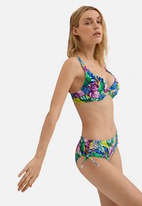 Bikini de estampado tropical multicolor con un top triangular y un corte ajustable en los lados, que presenta una textura suave y patrones de follaje vibrantes.