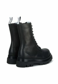 Stivali da combattimento in pelle nera con punta rotonda, allacciatura frontale e suole in gomma robuste. Presentano linguette di estrazione e dettagli di cucitura sui lati.