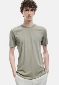 Herre kortærmet t-shirt i olivengrøn bomuld, rund halsudskæring, afslappet pasform, glat tekstur, uden synlige mønstre eller akcenter.
