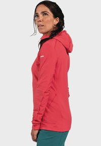 Rote leichte Kapuzenjacke mit strukturierten Ärmeln, tailliertem Design und einem Frontreißverschluss. Verfügt über eine verstellbare Kapuze und elastische Manschetten.
