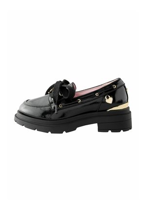 Schwarzer Lackleder-Loafer mit grober Sohle, großer strukturierter Schleife, goldenem Absatz-Akzent und kleinem Herzanhänger an der Seite.