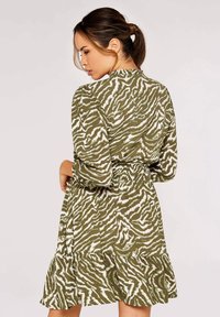 Grün-weißer Zebraprint-Kleid mit langen Ärmeln, tailliertem Bund und gerafftem Saum. Hergestellt aus leichtem Stoff mit strukturierter Oberfläche.