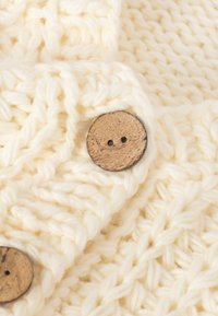 Țesătură groasă din tricot cu un model texturat, având două butoane circulare din lemn de culoare maronie cu două orificii. Material moale și gros.