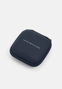 Navy blue zipper case with a smooth texture; features white "TOMMY HILFIGER" logo on the front, square shape, and reinforced edges.