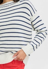 Gestreifter Strickpullover in Weiß mit marineblauen horizontalen Streifen, mit gerippten Bündchen und Saum sowie einer lässigen Passform.