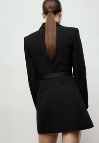 Zwarte blazer jurk met lange mouwen, getailleerde pasvorm, ceintuur in de taille en een uitlopende rok, met een gladde textuur en gestructureerde schouders.