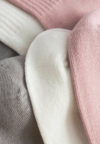 Drie paar sokken in roze, wit en grijs. De sokken hebben een geribbelde textuur en een gladde afwerking op de zolen.