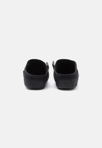Fekete slip-on cipők, texturált felsőrésszel, puha belső béléssel és lapos gumitalppal, finom oldalsó díszítésekkel.