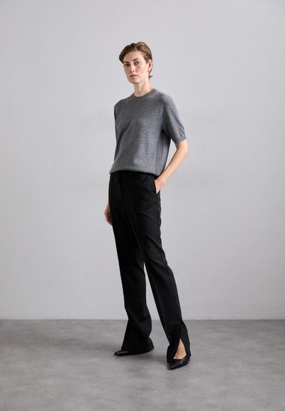 Gray knit short-sleeve sweater paired with black tailored trousers featuring a slit, complemented by pointed black heels. Smooth texture.