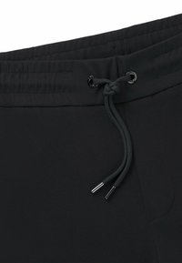 Svarta sweatpants med elastisk midja och dragsko, slät textur och subtilt tygmönster med metalländar på dragskon.