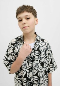 Trumpas rankovės marškinėliai su juodai baltu gėlių raštu, pagaminti iš lengvos medžiagos. Turi mygtukus užsegamą apykaklę ir laisvą siluetą.