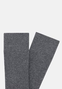 Calcetines de lana grises con una textura acanalada. Cuentan con un puño doblado y un acabado suave. Adecuados para un uso casual o diario.