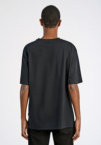 Camiseta de algodón negra de manga corta, con cuello redondo y un ajuste holgado. Textura suave sin patrones ni detalles visibles.