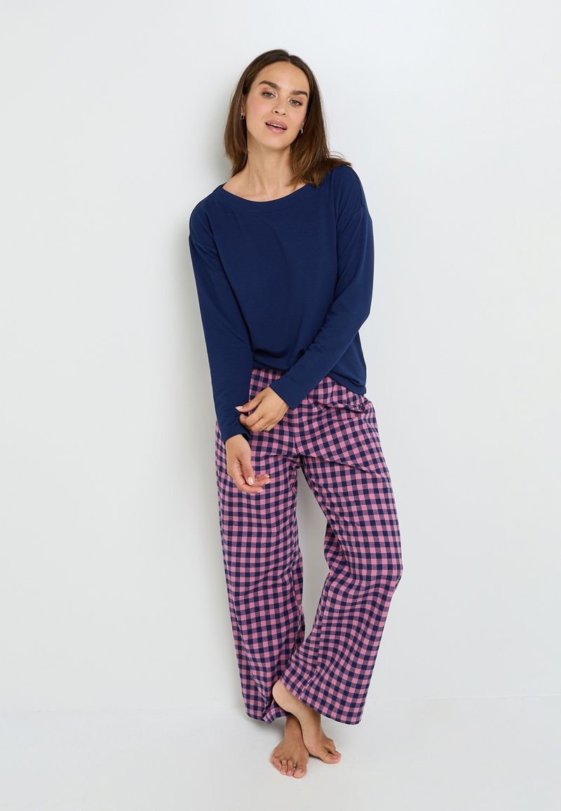 Chemise à manches longues navy assortie à un pantalon large à carreaux rose et navy, présentant une coupe décontractée et une texture de tissu douce.