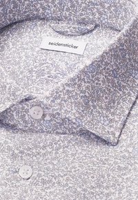 Camicia a fantasia floreale azzurro chiaro con tessuto testurizzato, dotata di colletto aperto e bottoni rotondi bianchi. L'etichetta interna riporta "seidensticker."