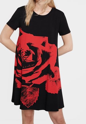 Femme portant une robe noire à manches courtes avec une grande impression de rose rouge et les mots "do it with love" à l'avant.