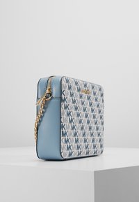 Borsa a spalla quadrata in pelle e tessuto blu chiaro. Caratterizzata da una stampa con logo blu e dettagli in catena dorata. Chiusura con zip nella parte superiore.