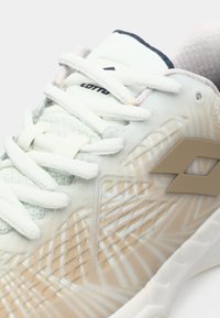 Atletická obuv Lotto s priehľadným, textúrovaným zvrškom v svetlozelenej a béžovej farbe. Má biele šnúrky a béžový logo akcent.