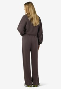 Ruskea löysä collegepaita ja siihen sopivat housut, joissa on joustava vyötärö, pitkät hihat ja teksturoitu kangas. Mukana myös rento urheiluvaatetus.