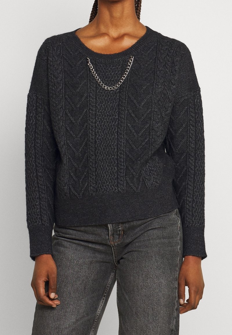 Pull en maille gris foncé avec un motif texturé, un large col et un détail en chaîne argentée sur le devant. Cuffs et ourlet côtelés.